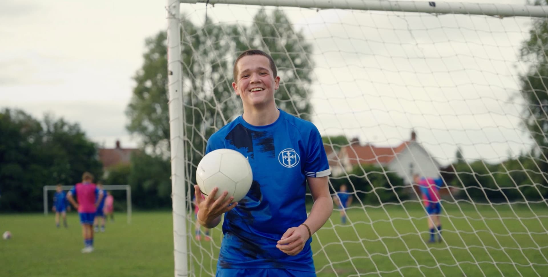The FA The Greater Game video production - smiling young footballer holding a ball in front of a goal, grassroots football content
